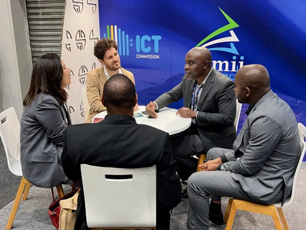 Lucia and Fabrizio meeting colleagues from Tanzania in front of an ICT Commission banner