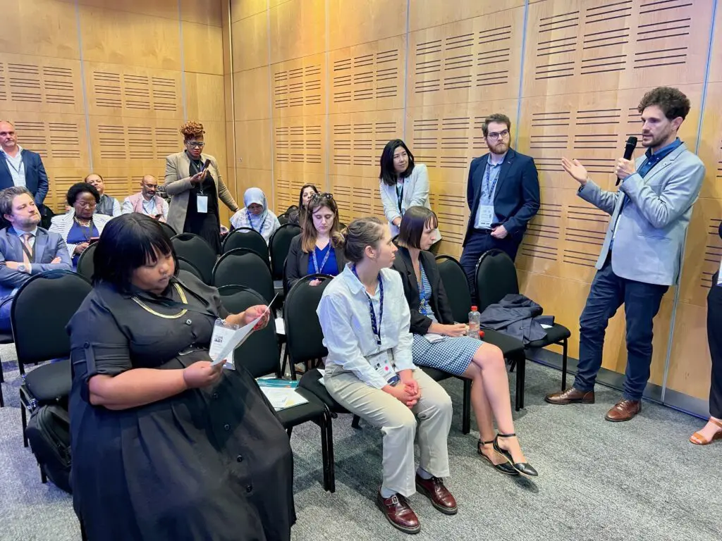 Fabrizio speaking with a microphone to a seated audience at the summit session