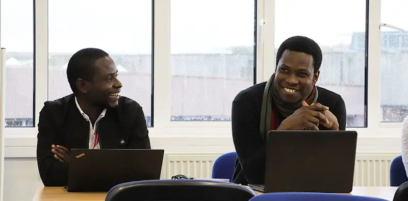 Ronald Waiswa and Michael Falade working at laptops at IDS