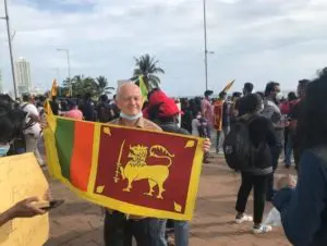 Man holding a Sri Lankan flag at a street protest