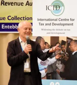 Mick Moore speaking into a microphone in front of an ICTD banner