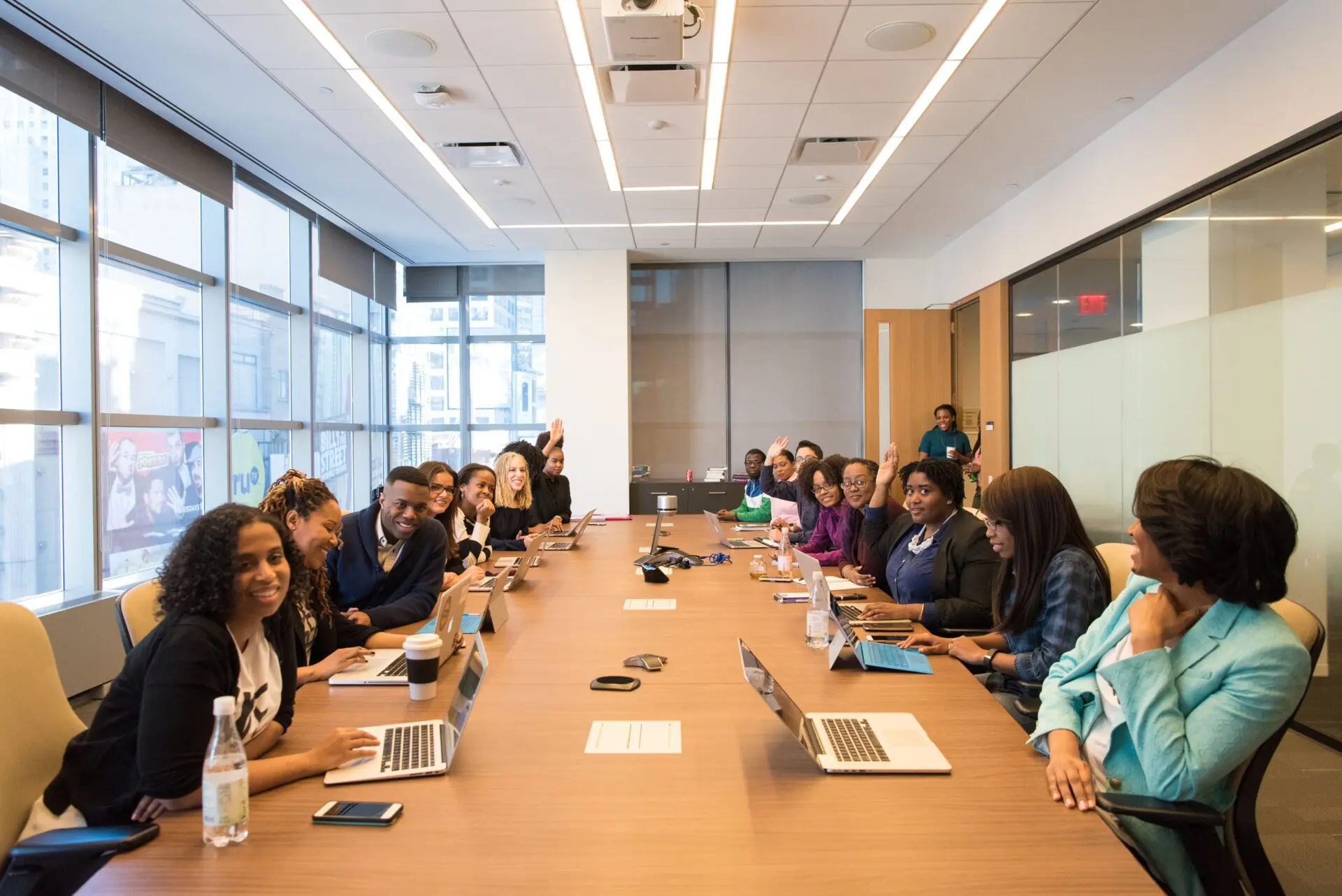 Group of people working on laptops around a long meeting table