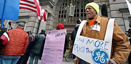 Protester holding a sign reading I paid more taxes than GE at a tax protest