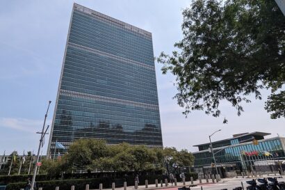 United Nations headquarters in New York, USA. Large, glass office block with trees in front of it.