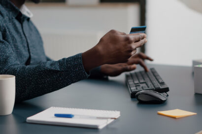 Close up of african american man hands typing credit card info on computer keyboard, online internet shopping leisure activity time. Business payment with web technology. Buying purchase transactions